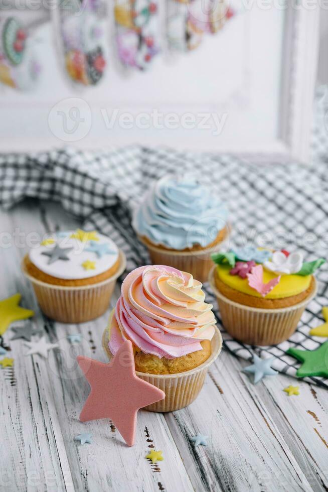Multiple colorful nicely decorated muffins on a wooden background photo