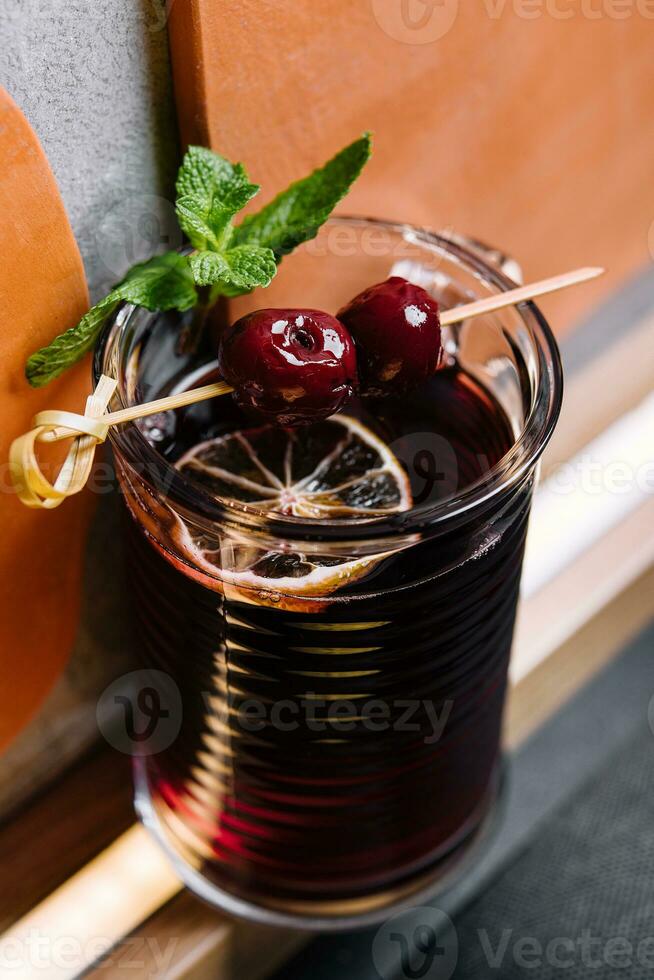 Glass of alcohol tincture made from cherry fruits photo