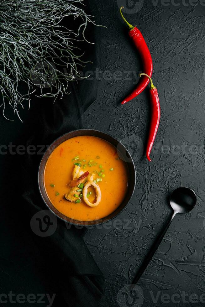 Tom yam seafood soup from above on black stone photo