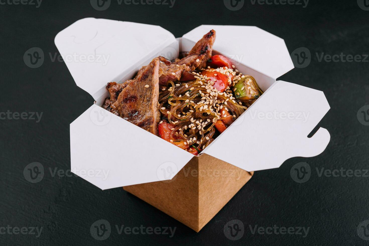 Close-up of noodles in a box with vegetables and beef in teriyaki sauce photo