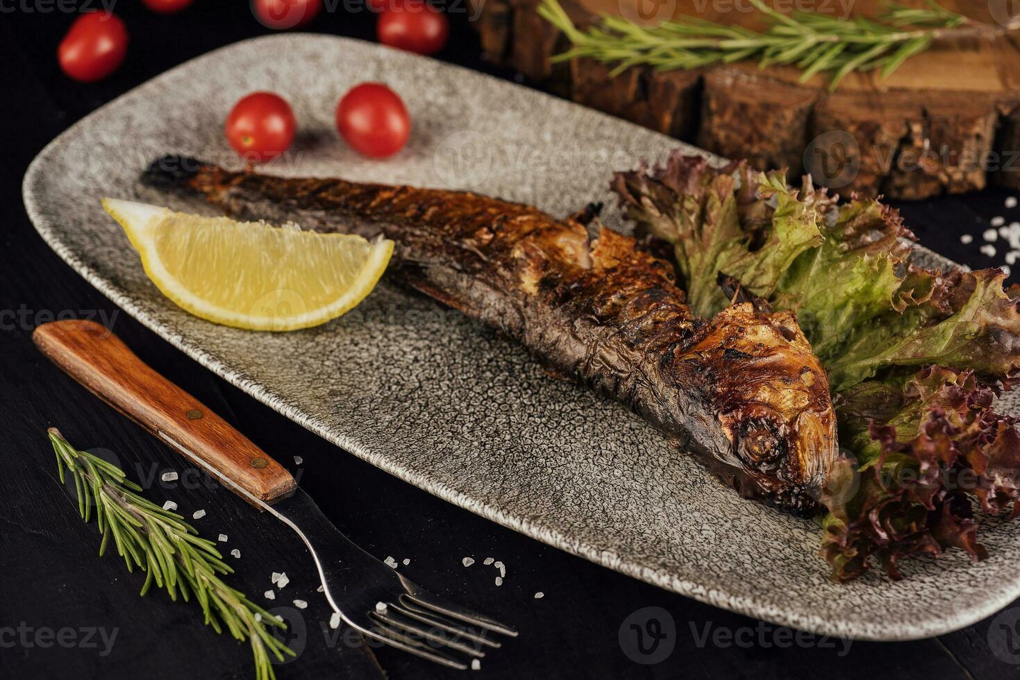 Fish dish - grilled herrings with cherry tomatoes photo