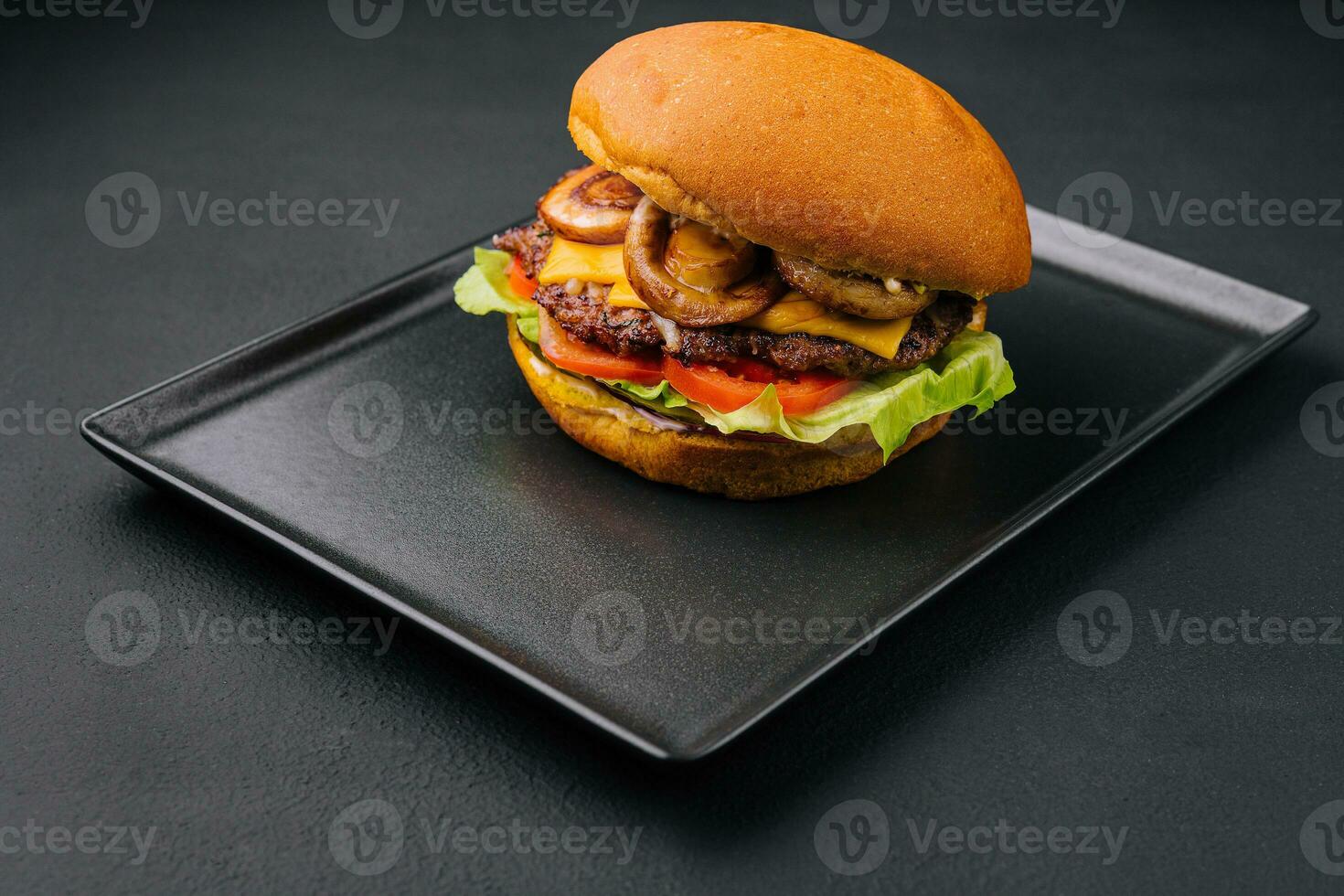 Burger with mushrooms and cutlet on black tray photo