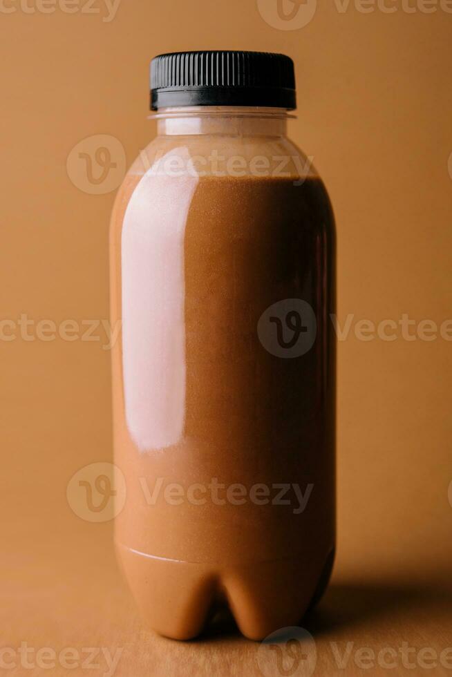 Brown smoothies in a bottle on a brown background photo