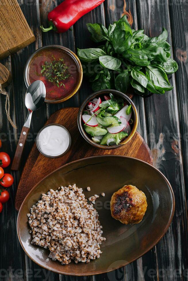 buckwheat with cutlet, borscht and salad photo