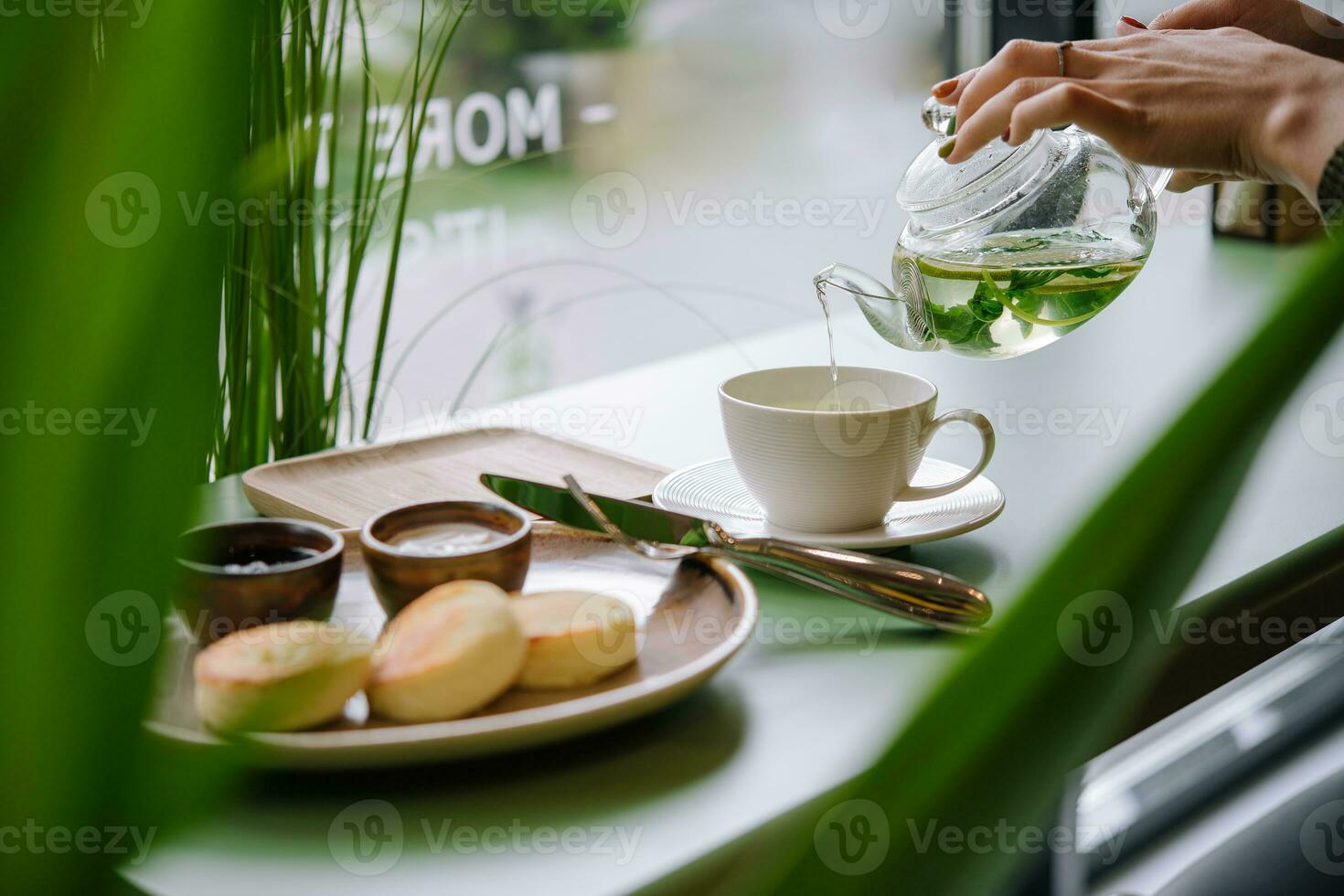 A hand pouring tea from glass teapot photo