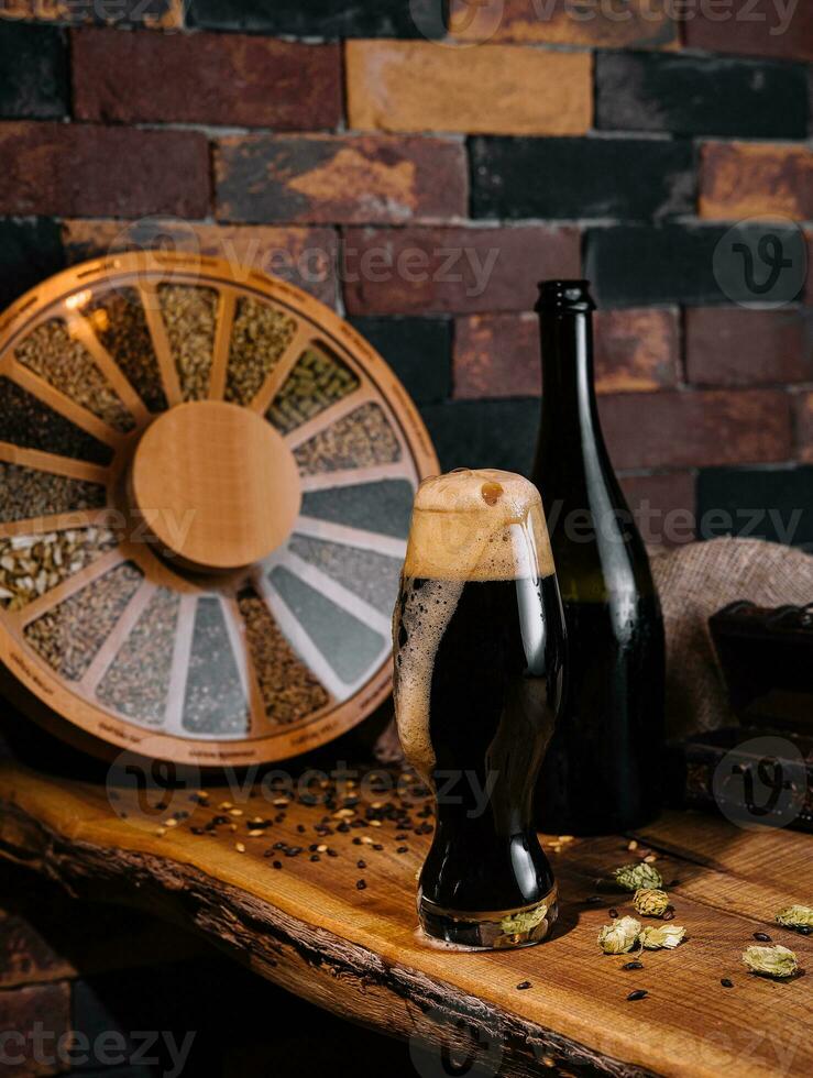 Glass of dark beer and bottle on wooden photo