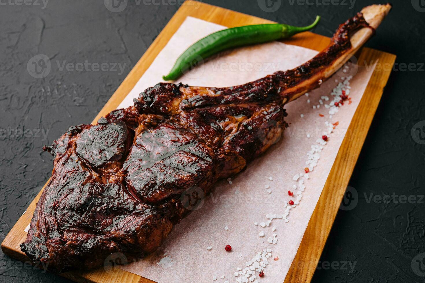 Freshly grilled Tomahawk steak on wooden cutting board photo