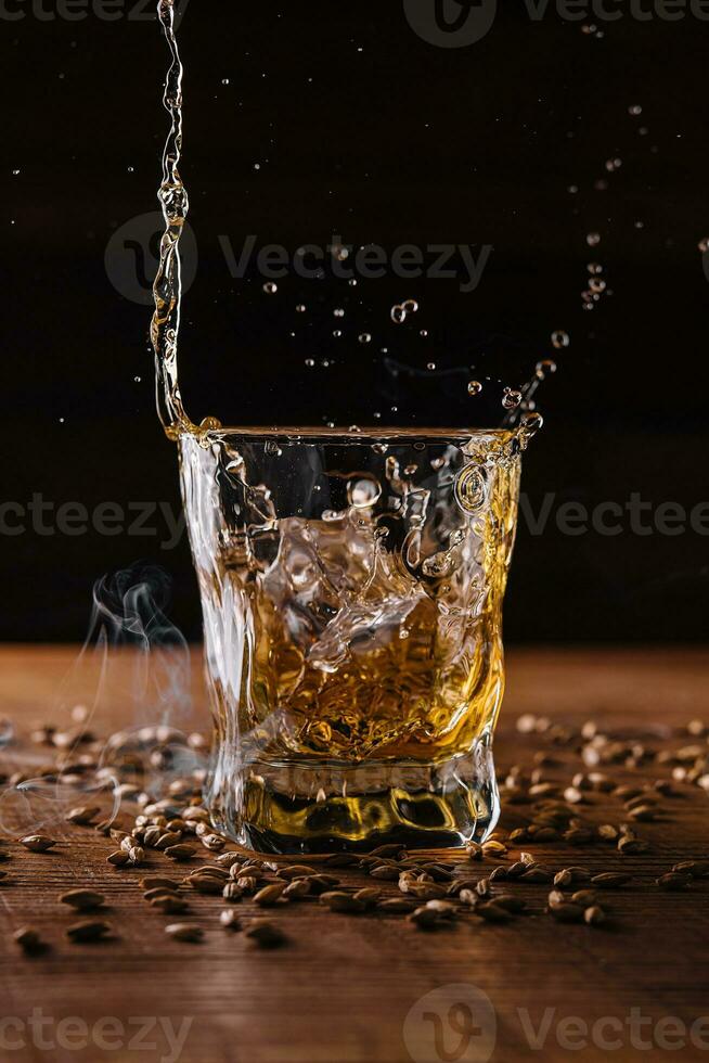 Splash of whiskey from an ice cube in glass photo