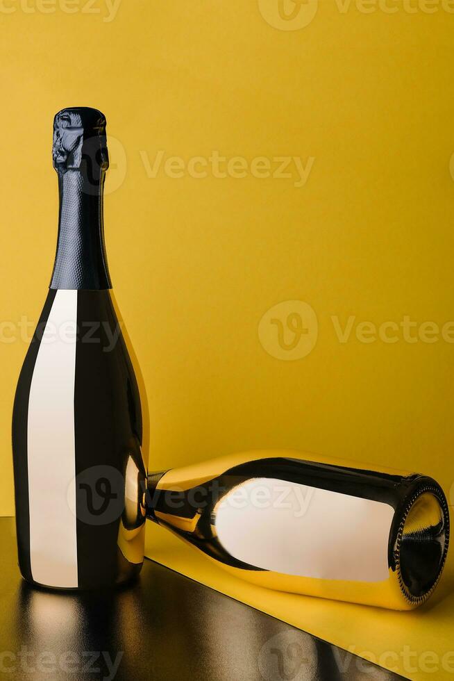 two golden bottles of champagne on yellow background photo