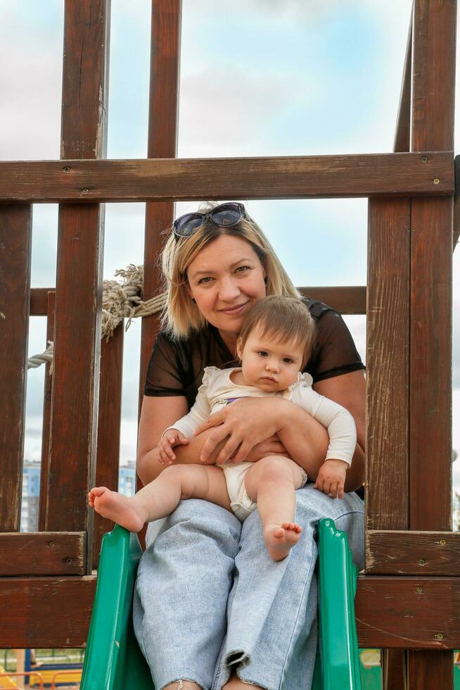 retrato de mamá y bebé hija en el patio de recreo foto
