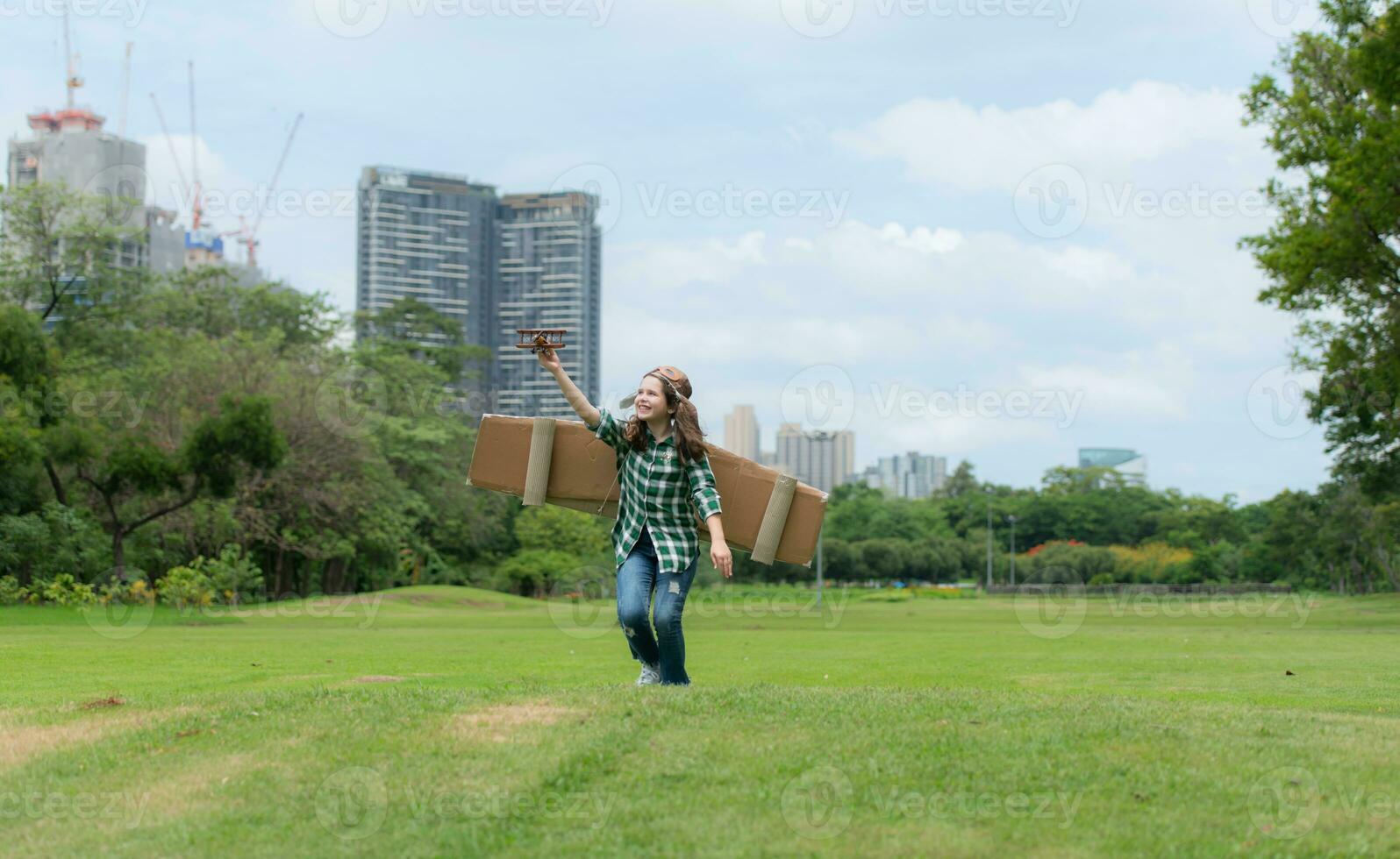 A little girl on vacation at the park with a pilot outfit and flying equipment. Run around and have fun with her dreams. photo