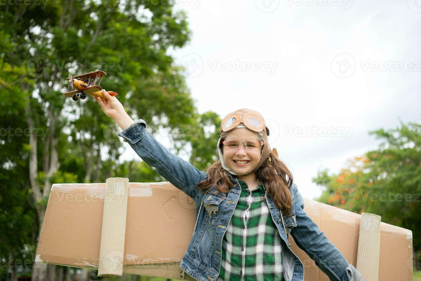 A little girl on vacation at the park with a pilot outfit and flying equipment. Run around and have fun with her dreams. photo