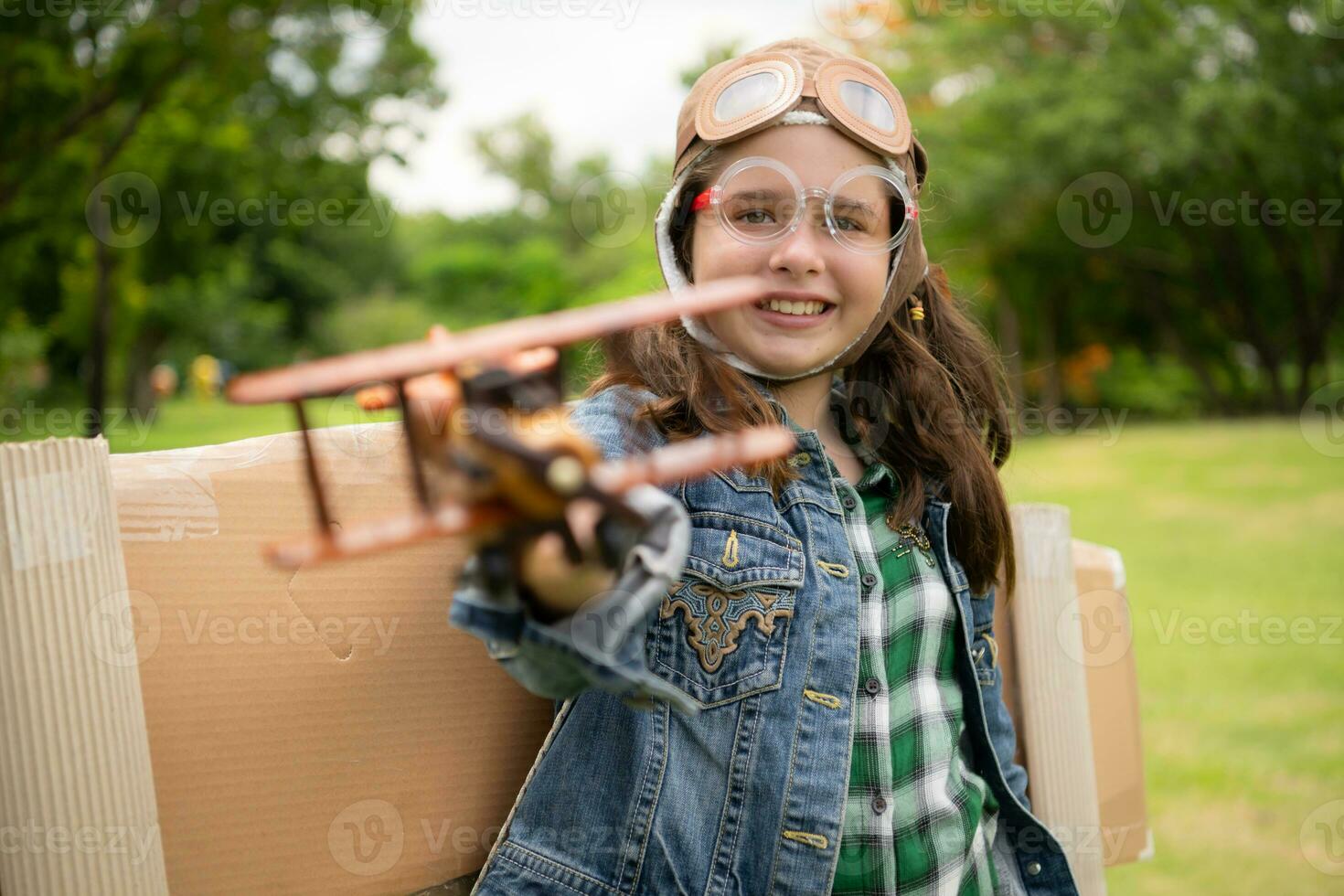 un pequeño niña en vacaciones a el parque con un piloto atuendo y volador equipo. correr alrededor y tener divertido con su Sueños. foto