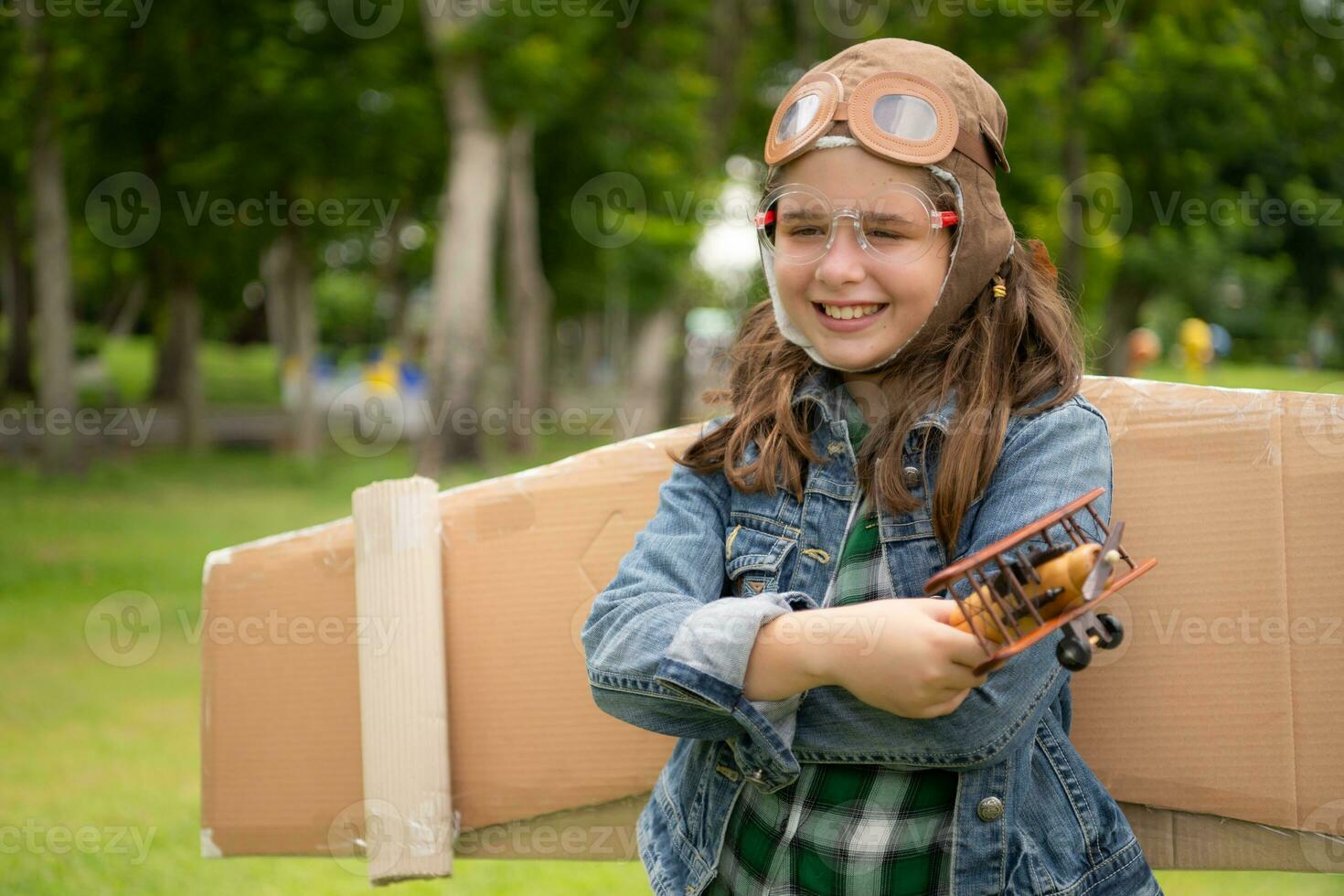 un pequeño niña en vacaciones a el parque con un piloto atuendo y volador equipo. correr alrededor y tener divertido con su Sueños. foto