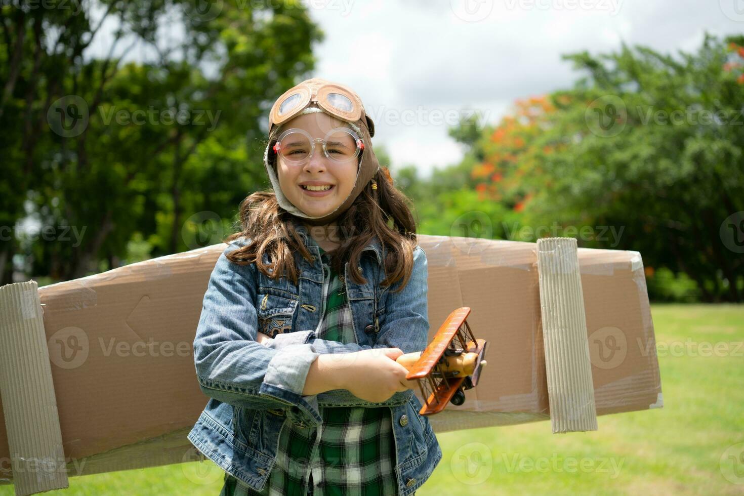 A little girl on vacation at the park with a pilot outfit and flying equipment. Run around and have fun with her dreams. photo