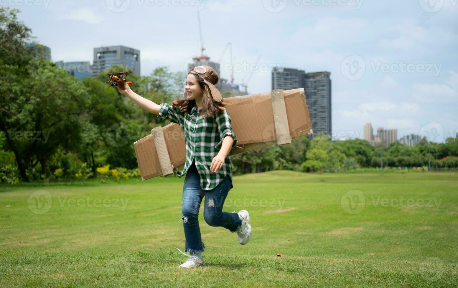 A little girl on vacation at the park with a pilot outfit and flying equipment. Run around and have fun with her dreams. photo