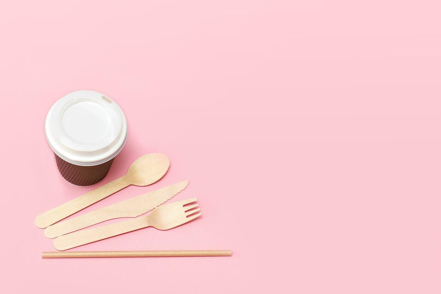 disposable tableware, glass, cutlery from recycled material on a pink background with copy space photo