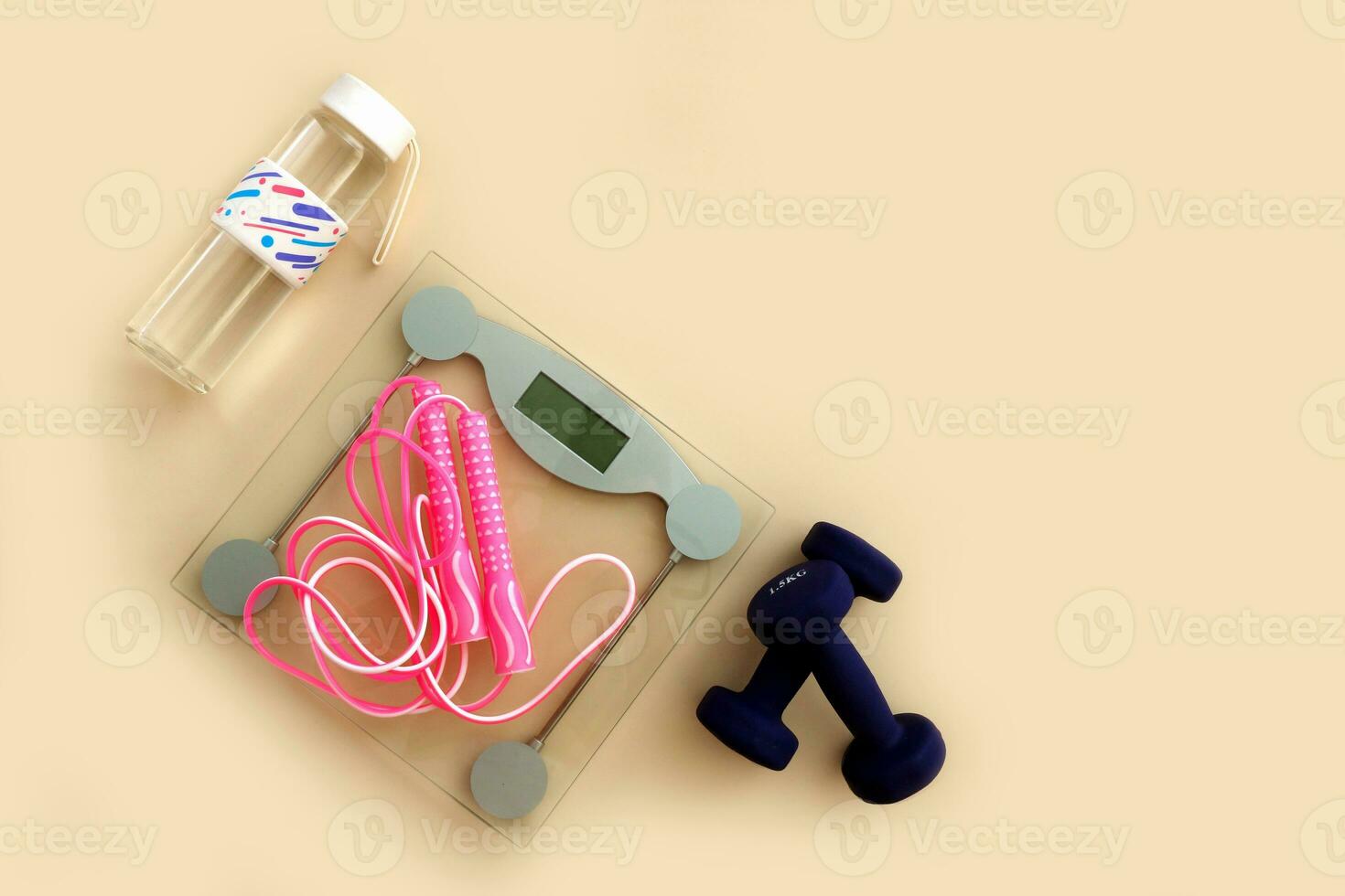 floor scales, jump rope, water bottle and dumbbells on a light background with copyspace, sports content photo