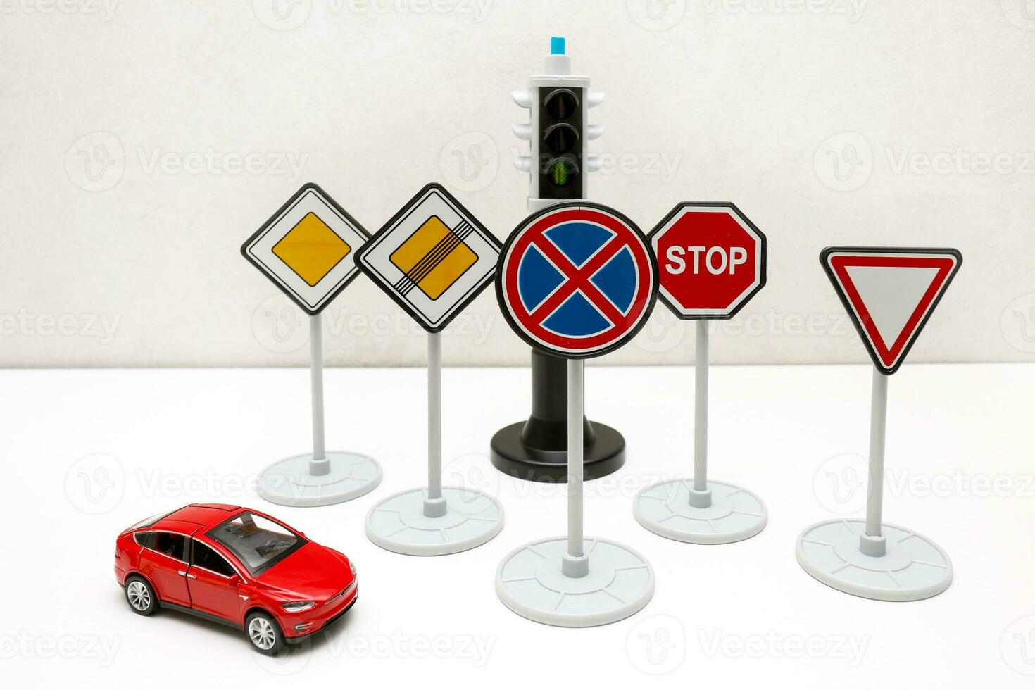 road signs, traffic lights and a toy red car on a light background photo