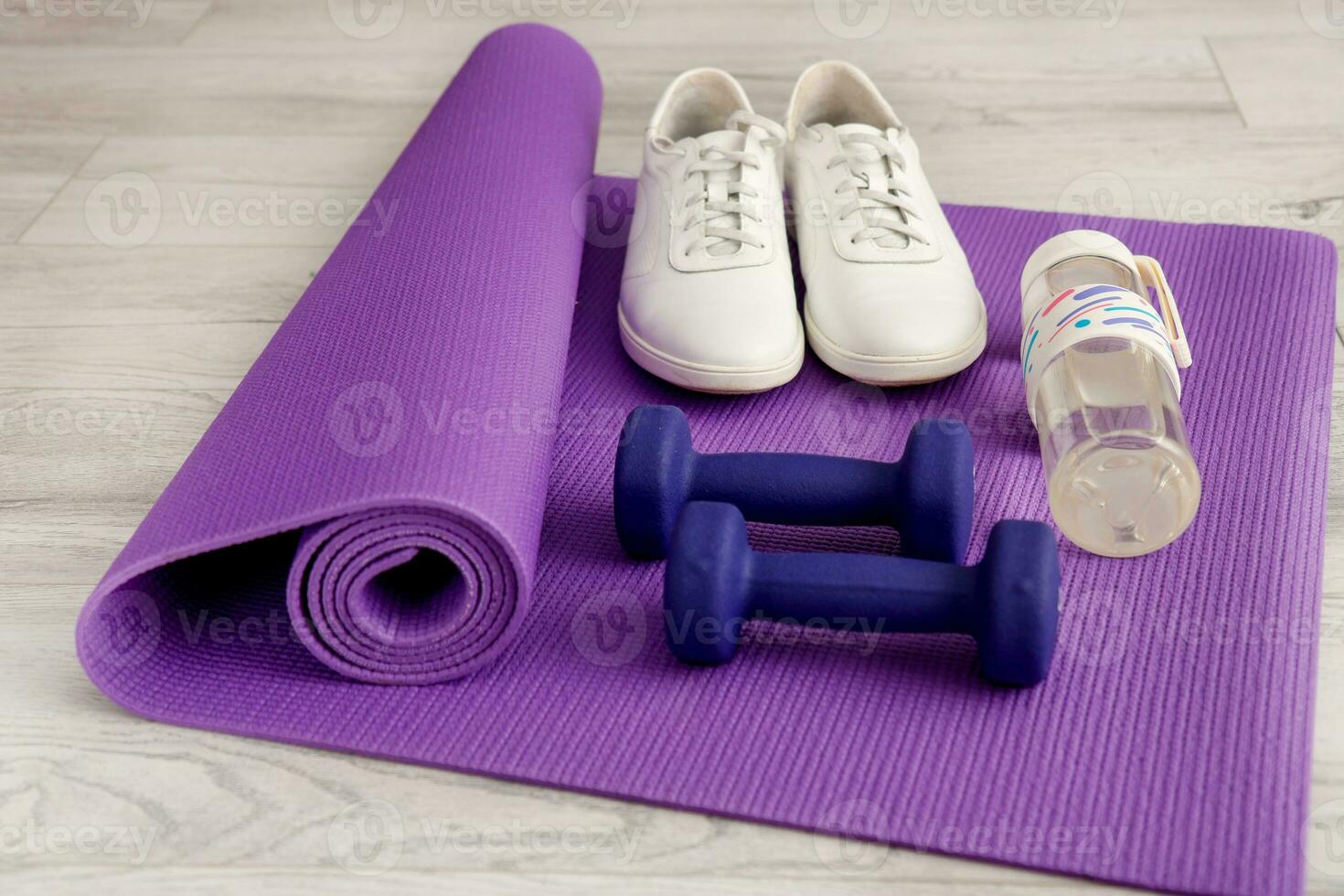 water bottle, sneakers, dumbbells on a gymnastic mat photo