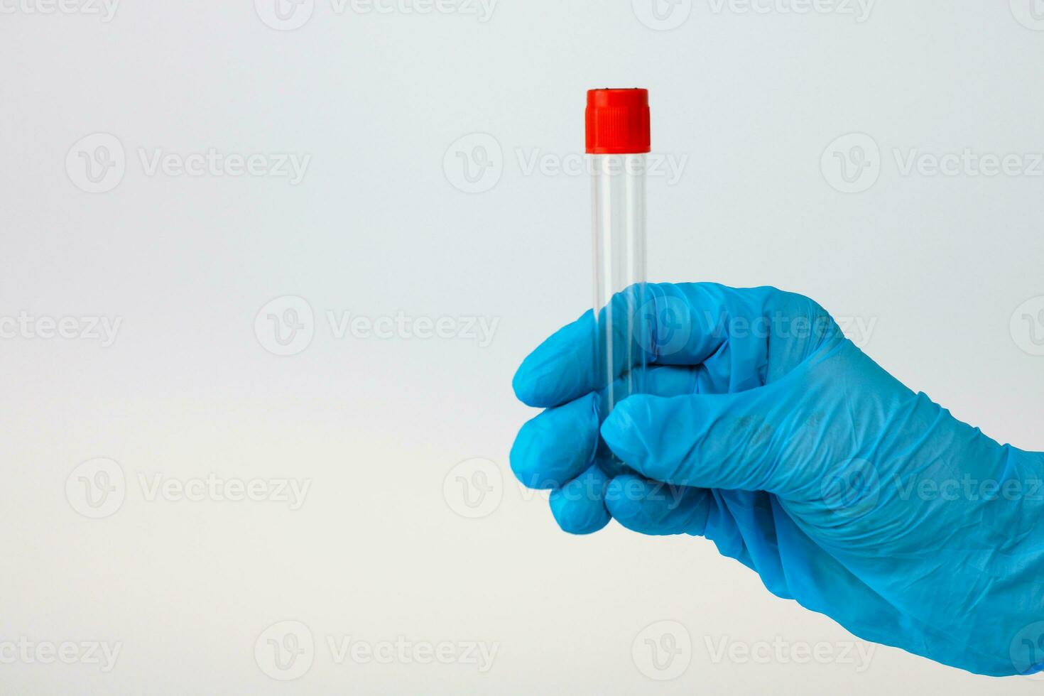 a hand in a medical glove holds an empty test tube on a light background with copy space photo