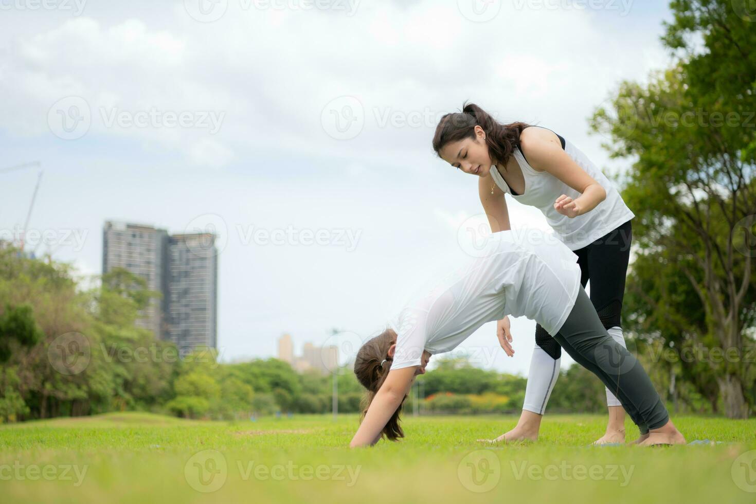 Young female and little girl with outdoor activities in the city park, Yoga is her chosen activity. photo