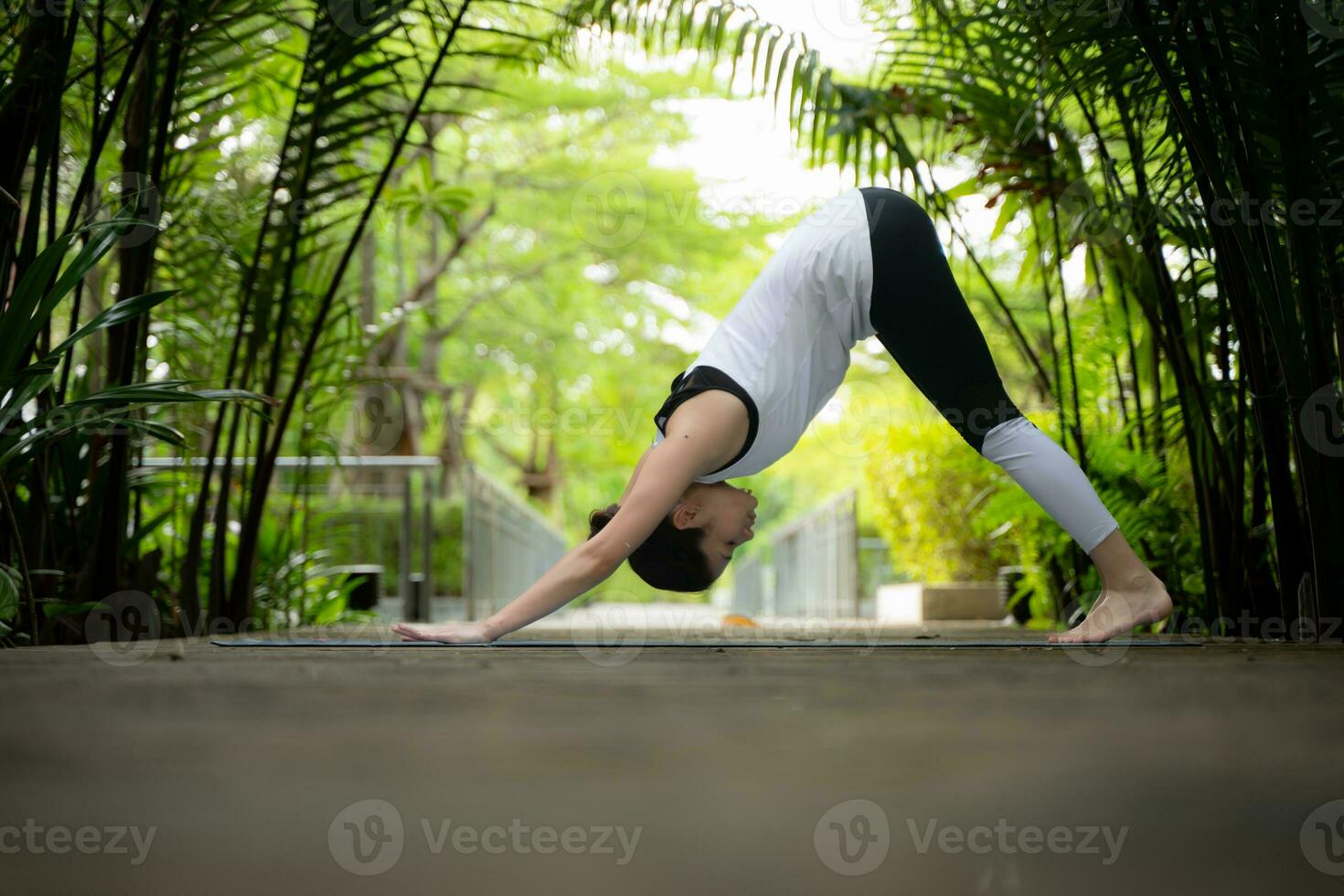 Young female in the garden there are wooden walkways and a tunnel of fresh green trees, with yoga activities for health photo