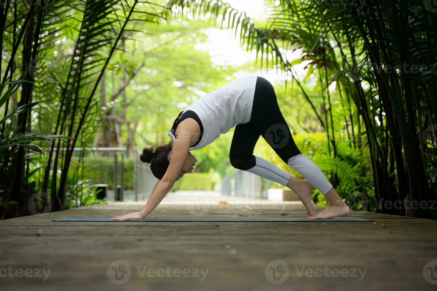 Young female in the garden there are wooden walkways and a tunnel of fresh green trees, with yoga activities for health photo