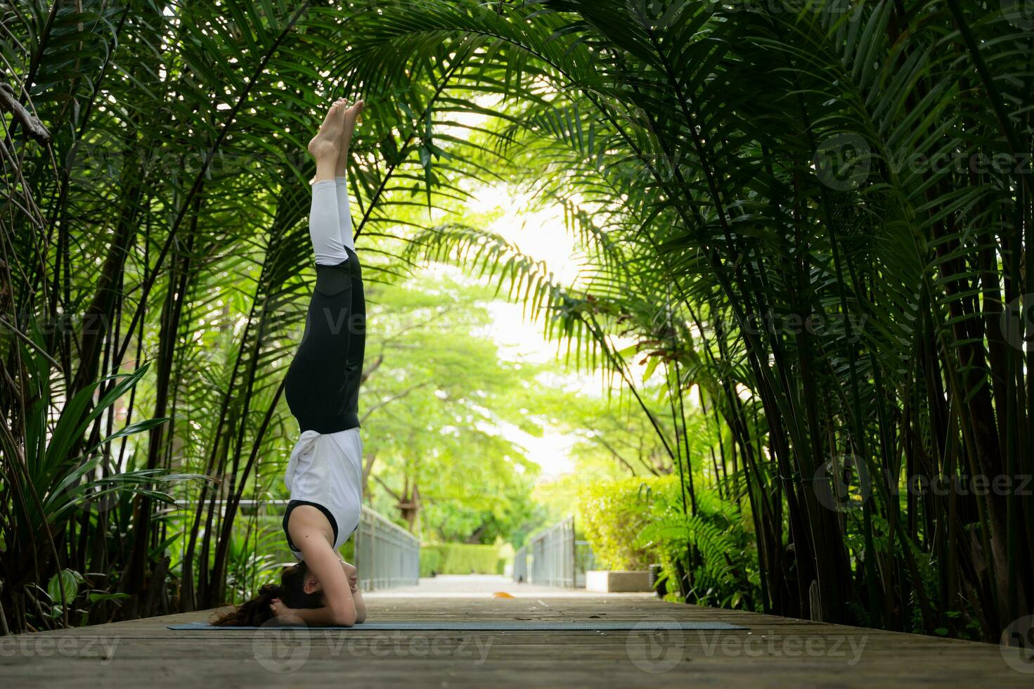 Young female in the garden there are wooden walkways and a tunnel of fresh green trees, with yoga activities for health photo