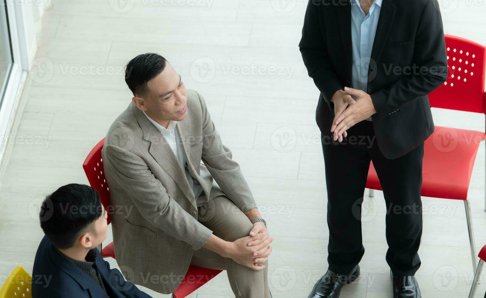 Confident Asian businessman sitting at chair and talking with his colleague in office photo