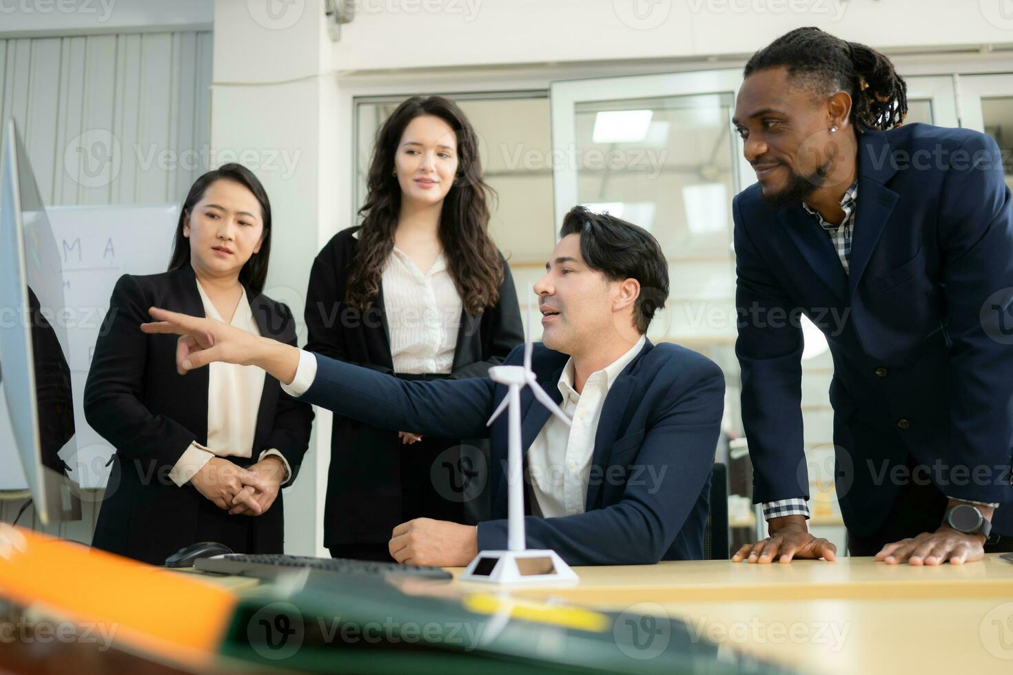 Diverse team of businessmen and engineers consultation on the engineering of a wind turbine that converts wind energy to electricity in the office. photo