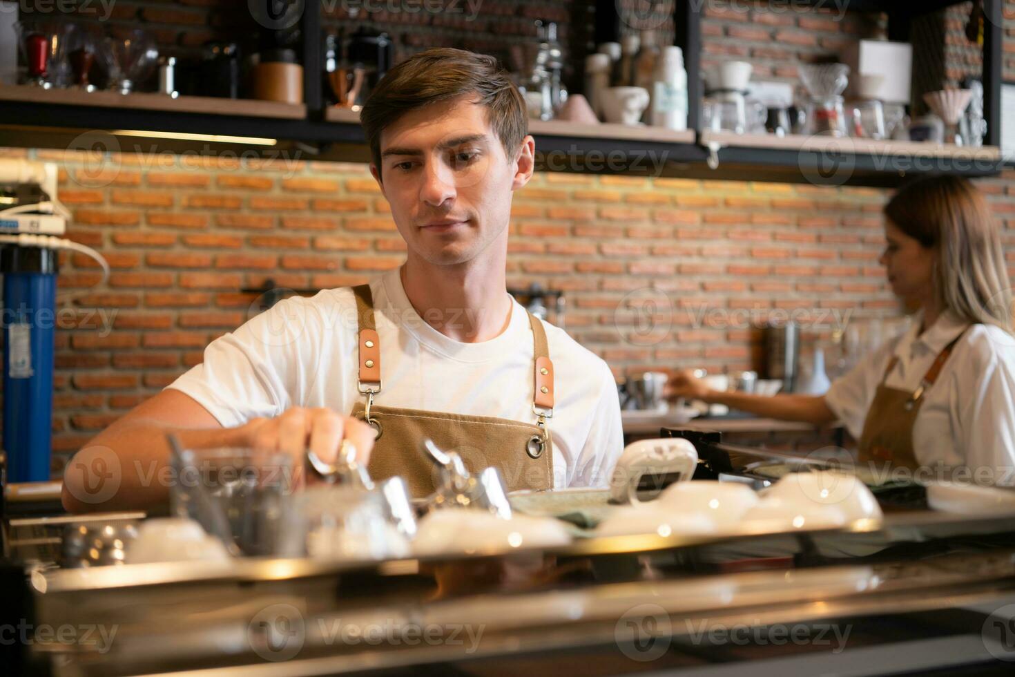 Barista working in cafe. Portrait of young male barista standing behind counter in coffee shop. photo