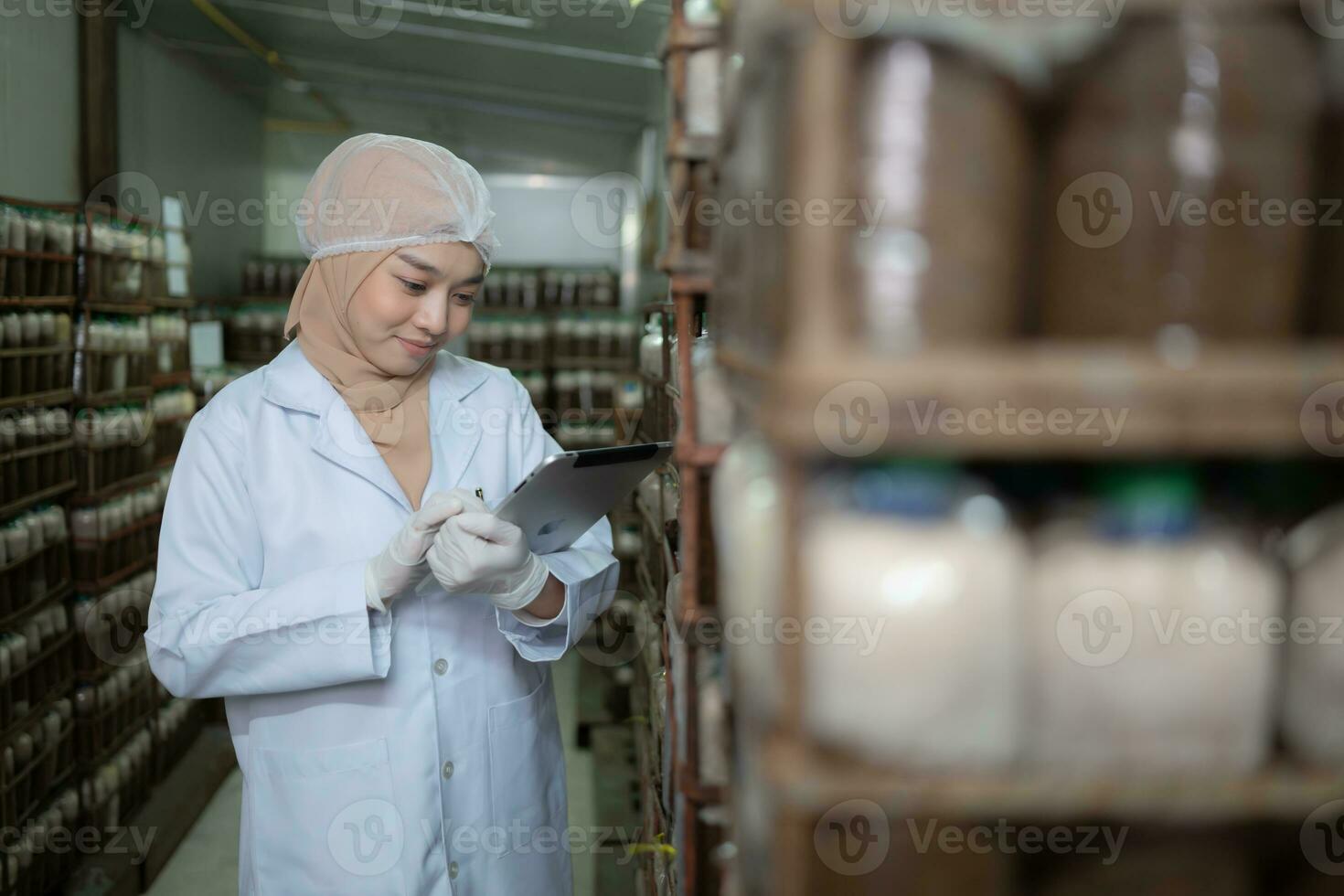 Young asian muslim female scientist doing research at a mushroom factory, examining mushroom leavening agent in a sterile and temperature-controlled room. photo