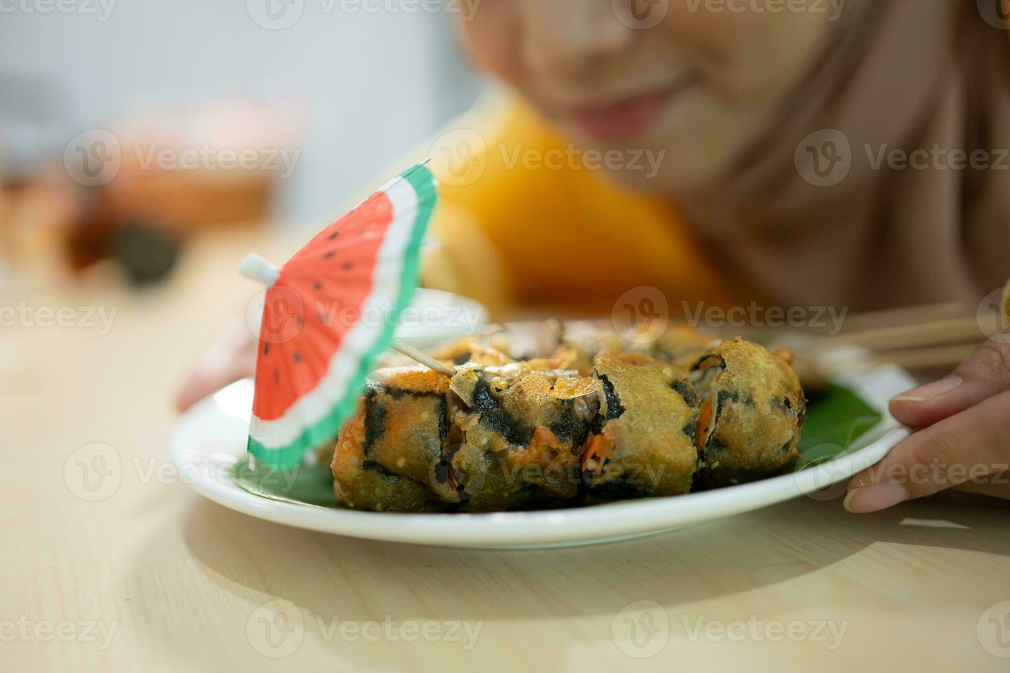 Muslim girl eating mushroom sushi at the restaurant. Selective focus on sushi photo