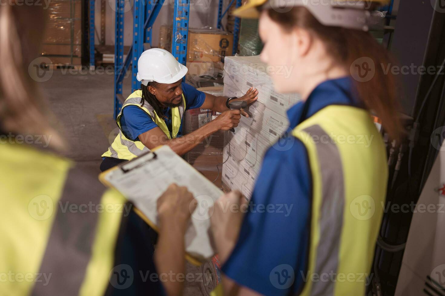 Warehouse workers work together in a large warehouse. A male employee is scanning the contents of a box on a forklift. photo