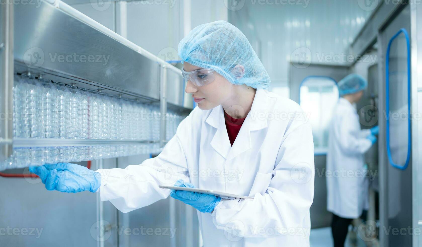 Female quality control worker inspecting water bottle on production line in drinking water factory photo