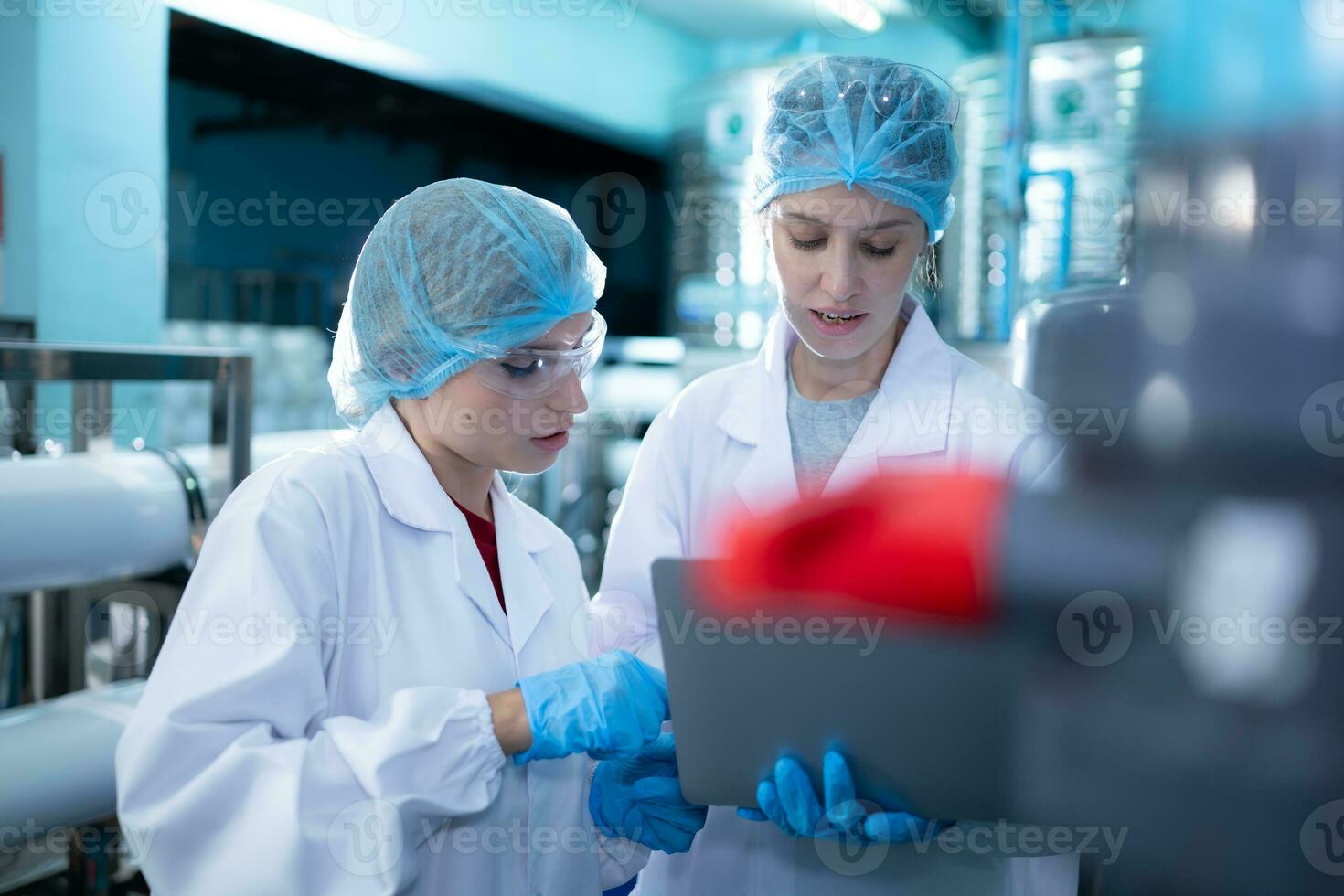 Two young female scientists working with tablet computer in drinking water plant photo