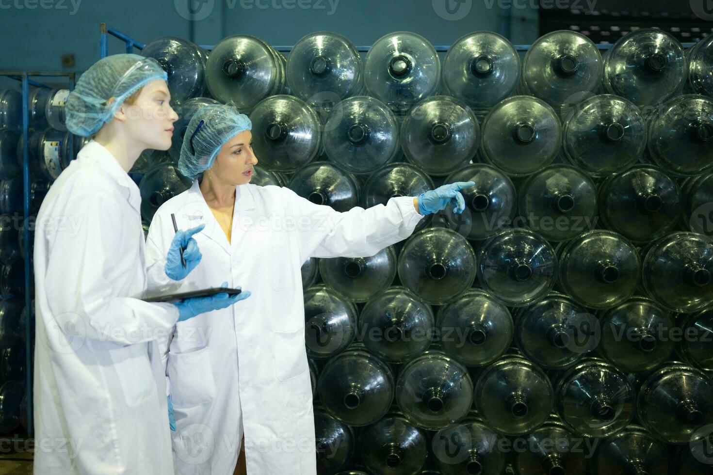 Both of female quality control workers in a drinking water factory Inspecting the quality of water tanks before importing the drinking water belt into the tank photo