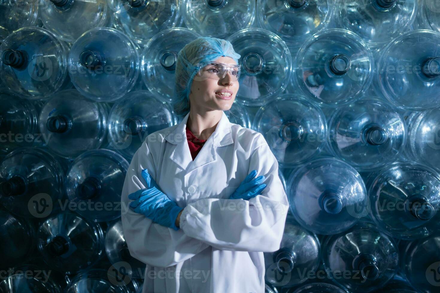 retrato de hembra científico con brazos cruzado en Bebiendo agua fábrica, ella estaba en pie en frente de un el plastico botella. foto