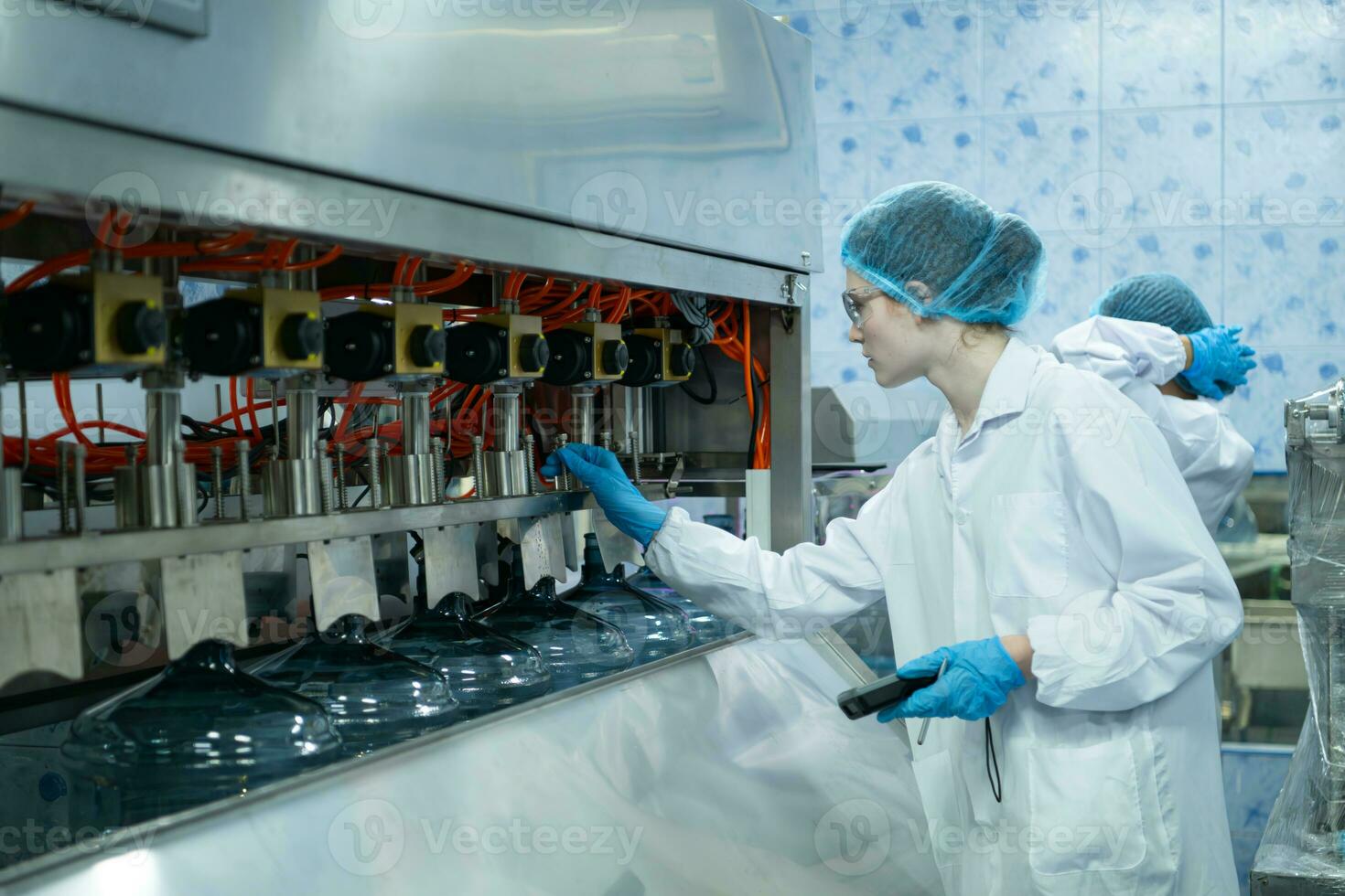 Female scientist in white coat and blue hat working in the control  machine of production line. photo
