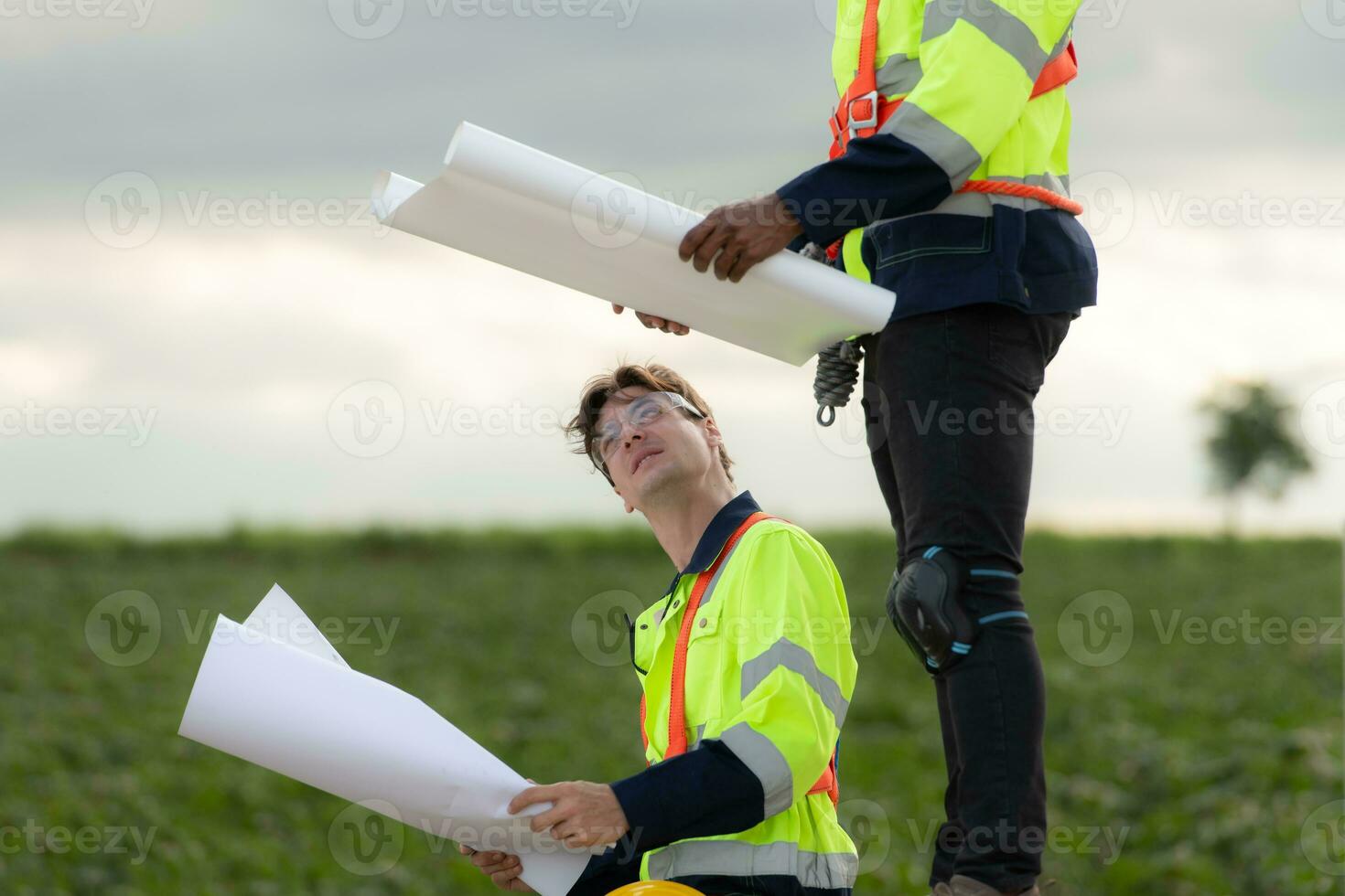 ingenieros y técnicos trabajo juntos en el torre base de un grande viento turbina con un viento turbina campo en el fondo, el concepto de natural energía desde viento. foto