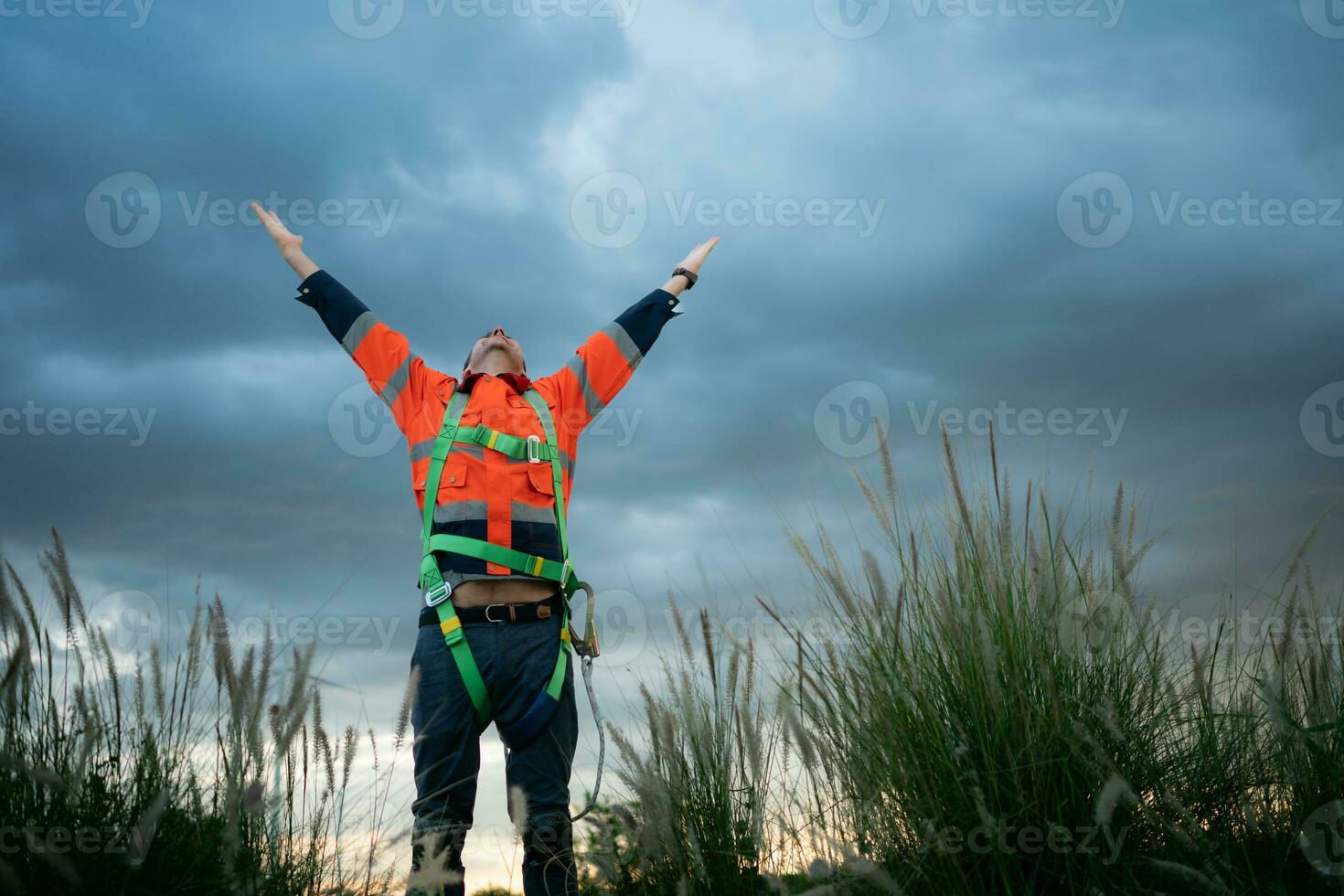 Young engineer working in a wind turbine field wear a safety vest raise both hands to relax after finishing the wind turbine inspection mission photo