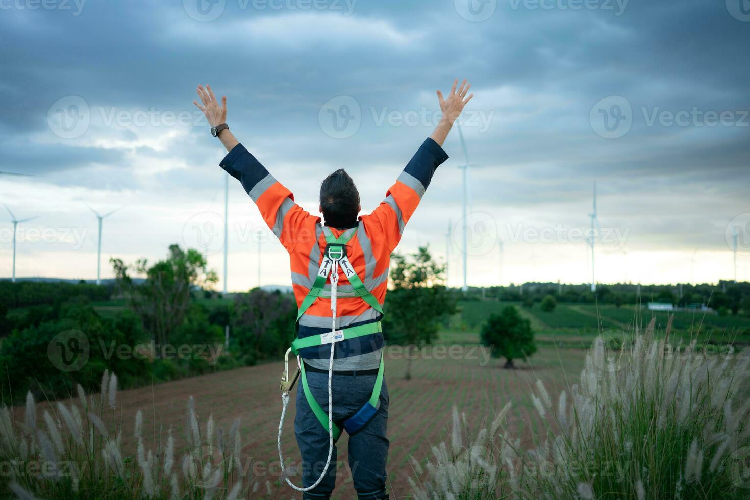 Young engineer working in a wind turbine field wear a safety vest raise both hands to relax after finishing the wind turbine inspection mission photo