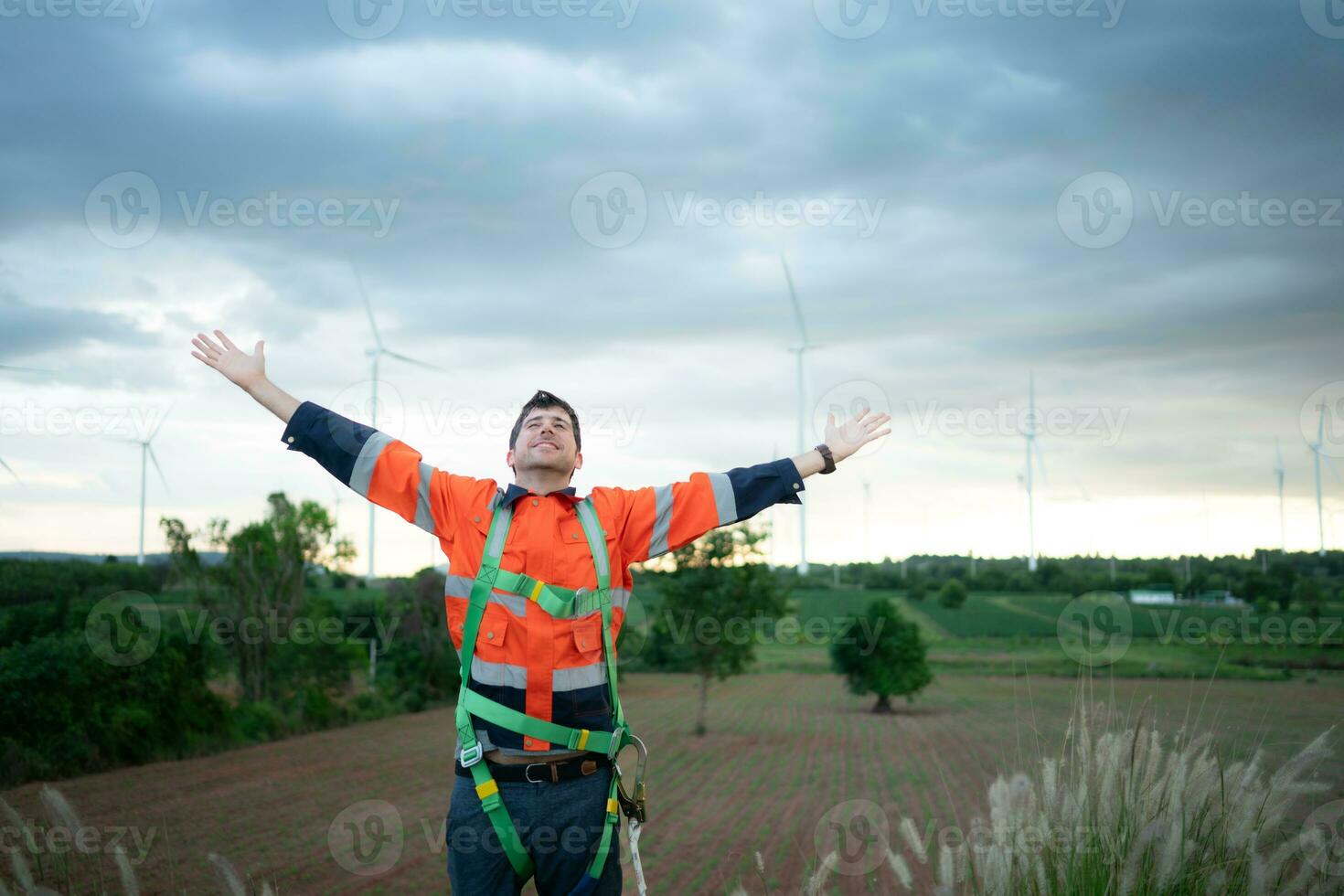 Young engineer working in a wind turbine field wear a safety vest raise both hands to relax after finishing the wind turbine inspection mission photo