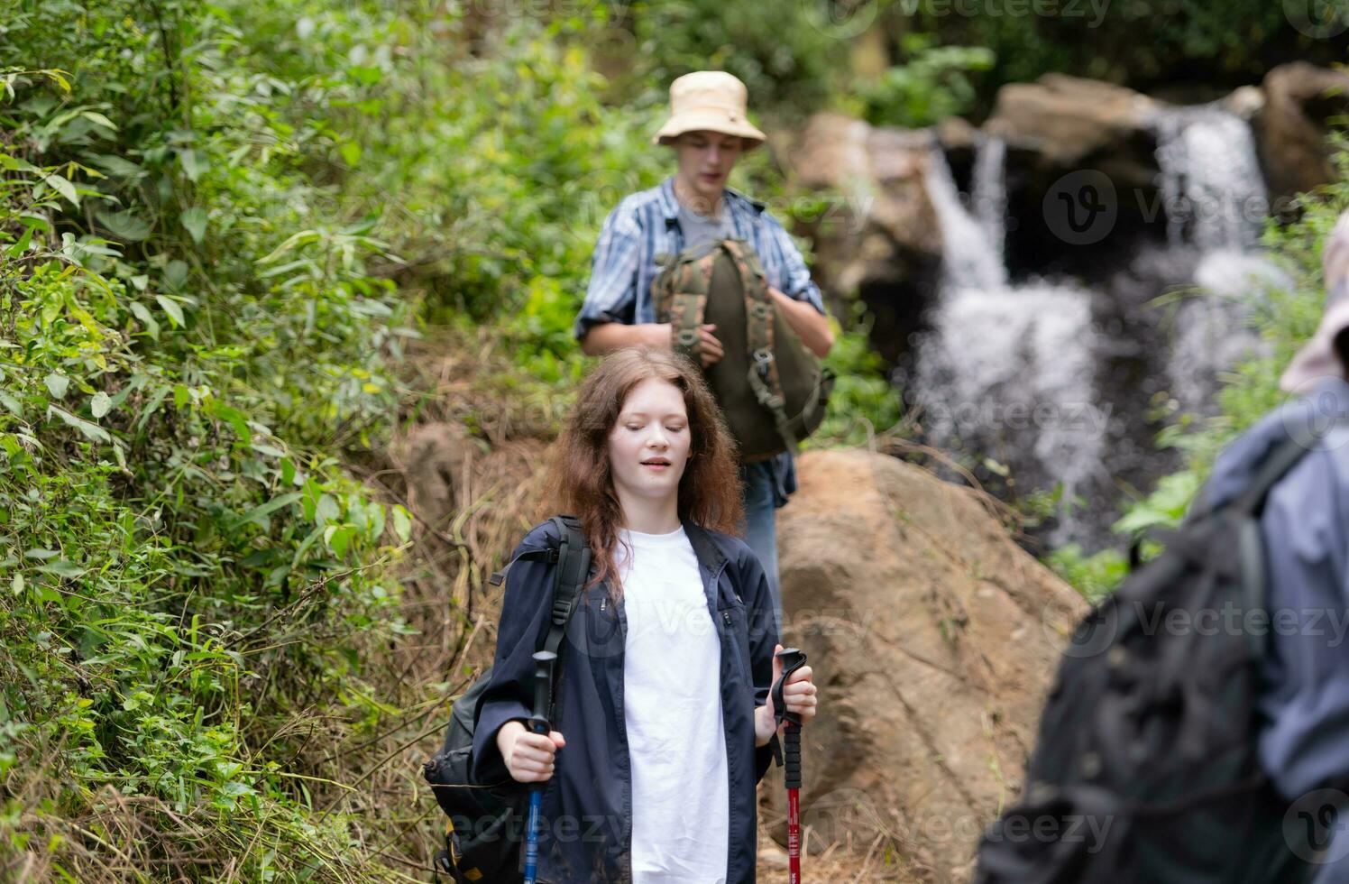 Group of friend on a sunny day in the forest Young group hiker with backpack and trekking poles photo