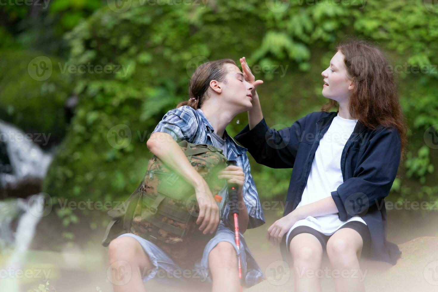 Young couple hiking in the forest with backpacks and trekking poles photo