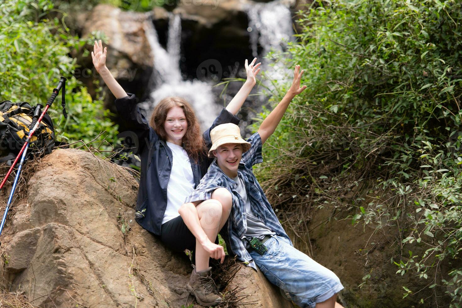 Young couple of hikers sitting on a rock and kissing photo