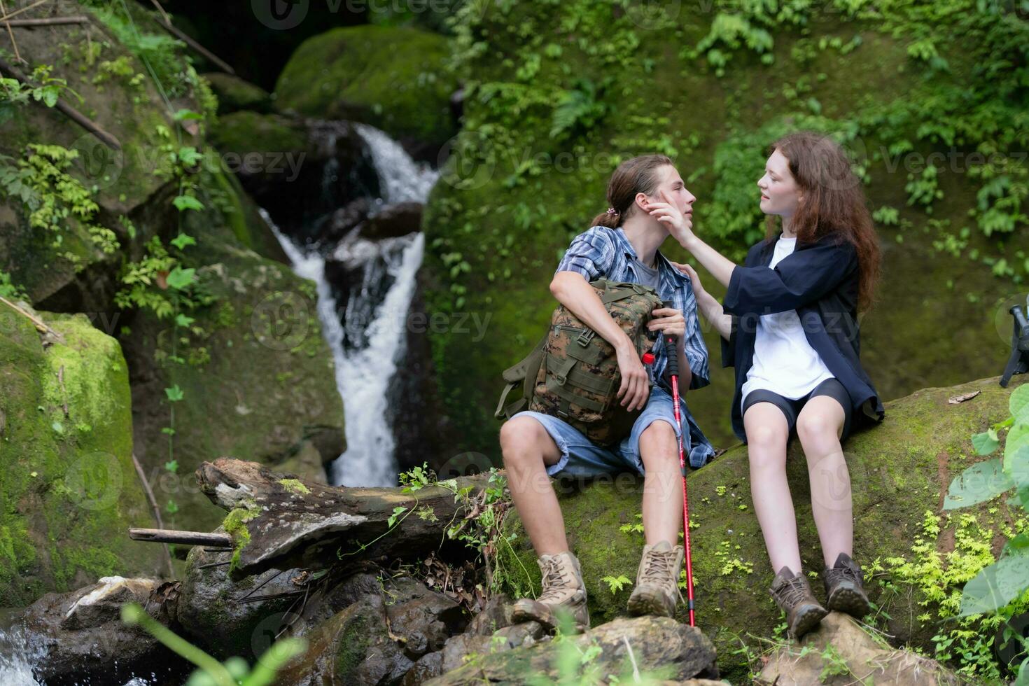 Young couple hiking in the forest with backpacks and trekking poles photo