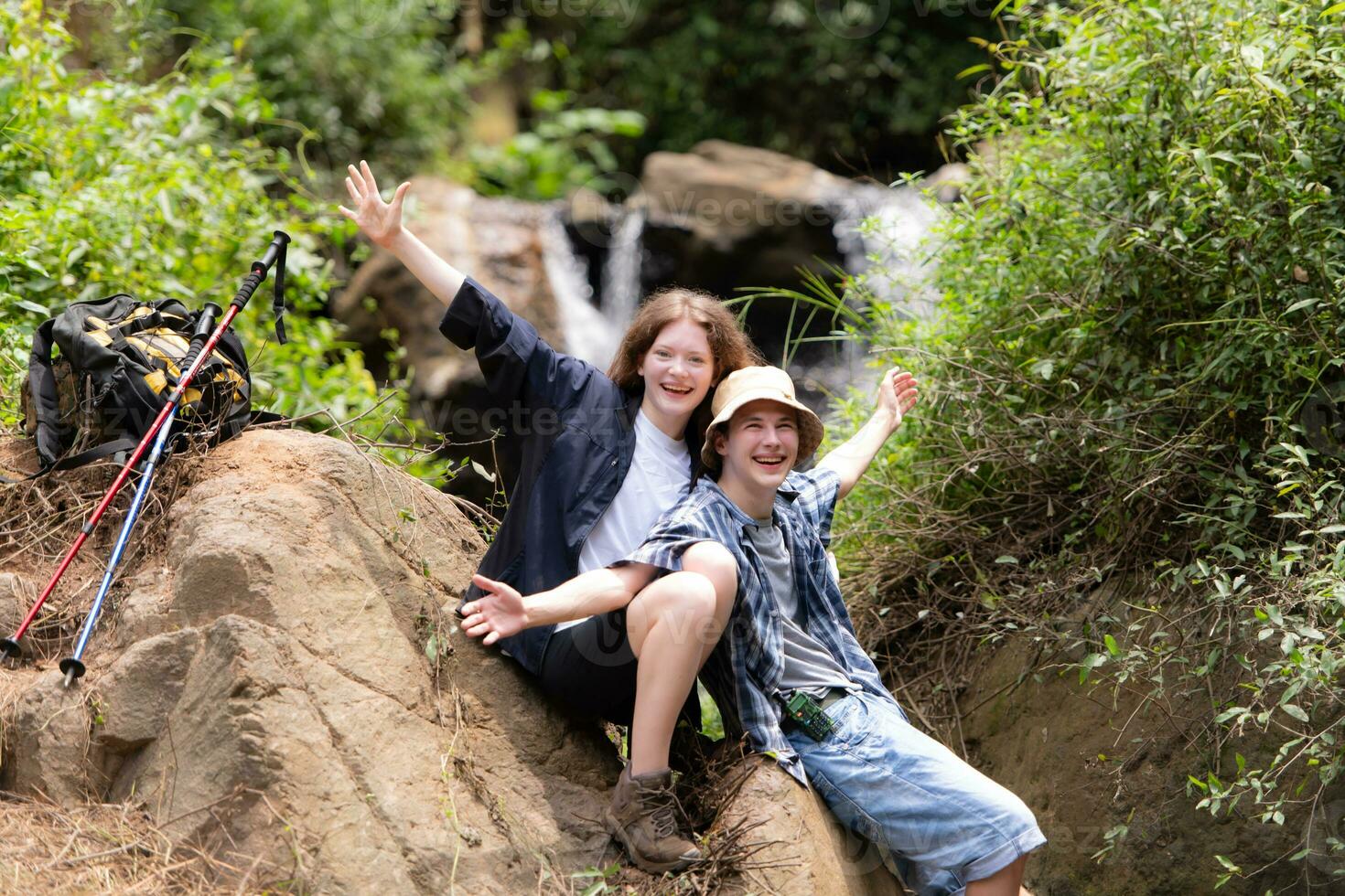 Young couple of hikers sitting on a rock and kissing photo