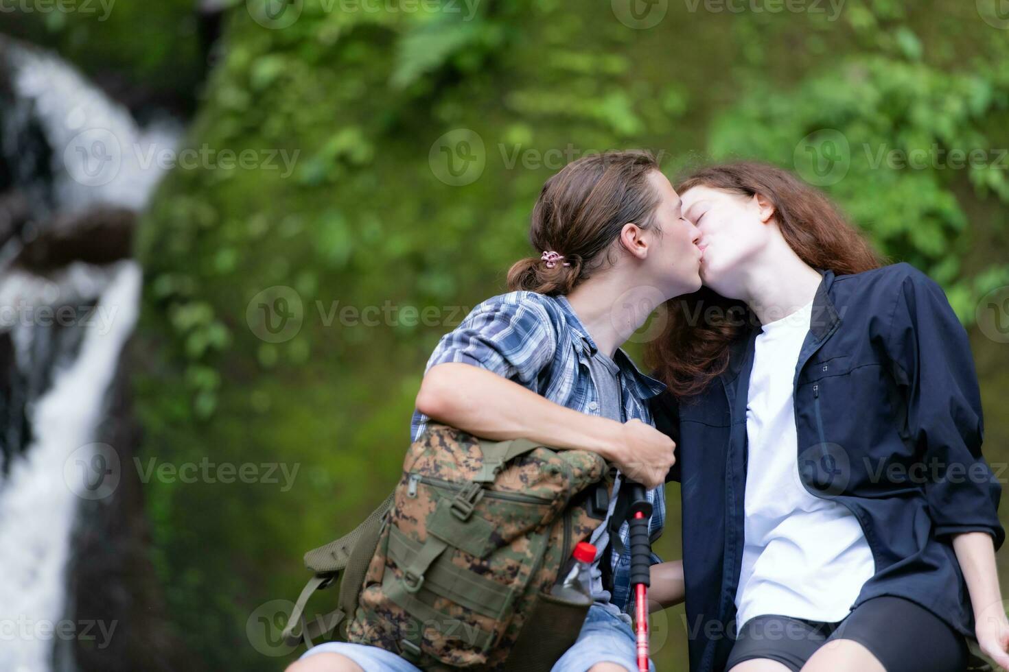 Young couple hiking in the forest with backpacks and trekking poles photo